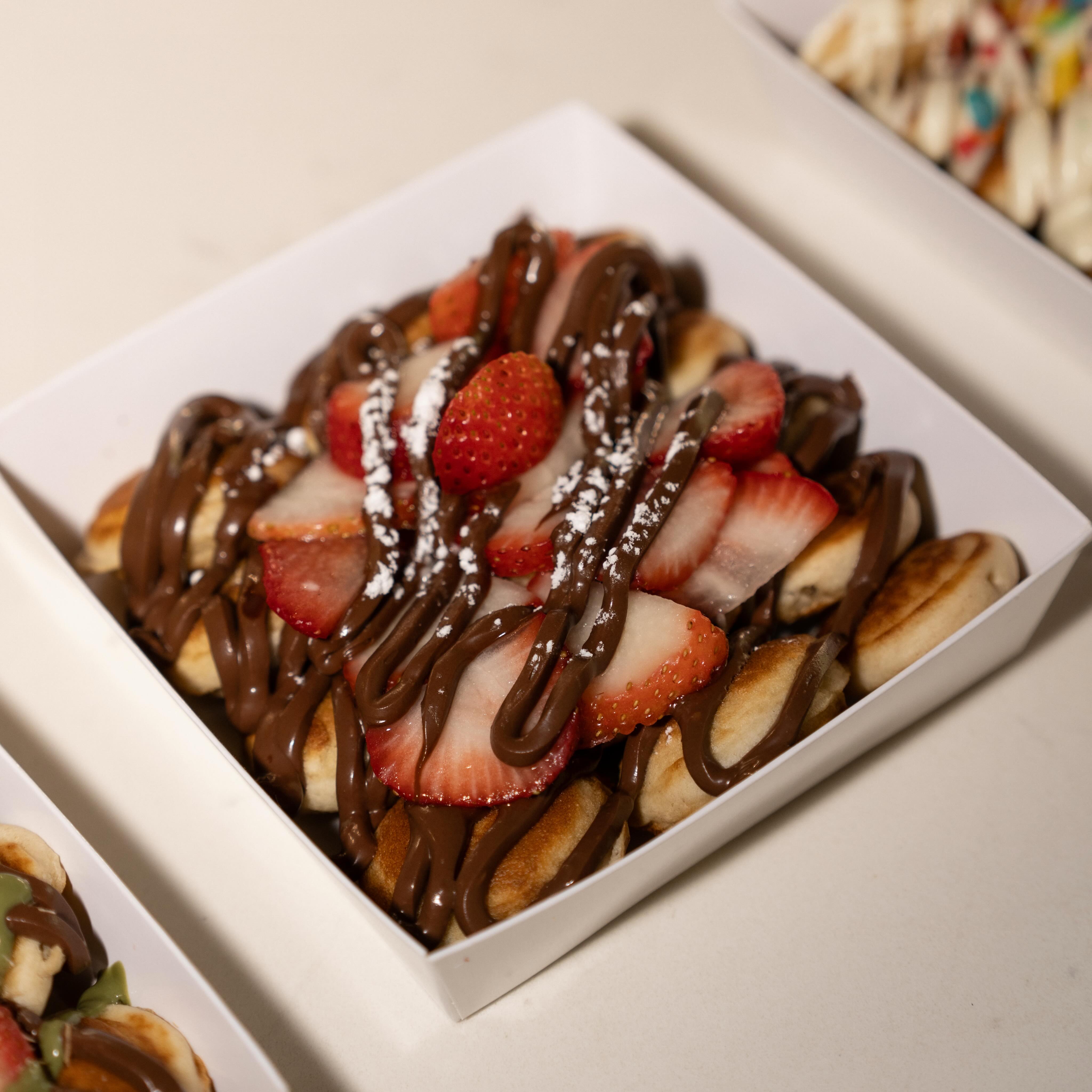 Mini pancakes with Dubai chocolate and strawberries in a takeaway box